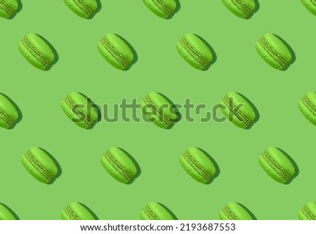 Macaroons. Pattern in minimal style. Pistachio french biscuits on bright green backdrop 