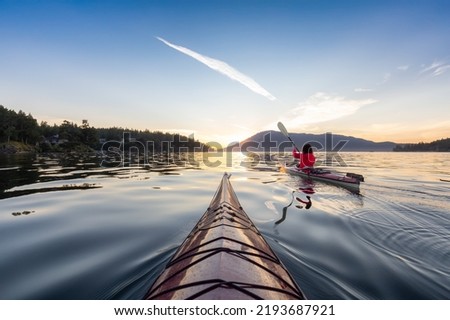 Adventurous Woman on Sea Kayak paddling in the Pacific Ocean. Sunny Summer Sunset. Taken near Victoria, Vancouver Islands, British Columbia, Canada. Concept: Sport, Adventure Royalty-Free Stock Photo #2193687921