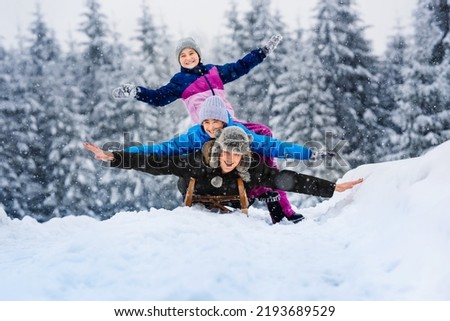 Happy family father, daughter and son are sledding in snow. Happy winter holidays. Royalty-Free Stock Photo #2193689529