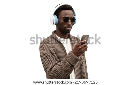 Portrait of stylish african man with smartphone in wireless headphones listening to music isolated on white background