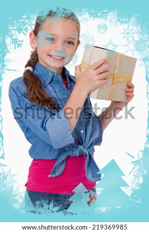 Composite image of Portrait of a happy girl holding a gift box with christmas frame