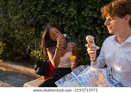 Girlfriend takes pictures of her boyfriend with the analog camera while they eat ice cream and are on vacation