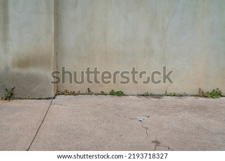 urban texture and background old gray grunge building wall and concrete pavement with some green weeds