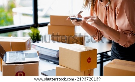 A woman using a smartphone to take pictures in front of parcel boxes, parcel boxes for packing goods, delivering goods through private courier companies. Online selling and online shopping concepts. Royalty-Free Stock Photo #2193720139