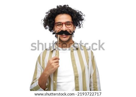 party props, photo booth and people concept - smiling young man with mustache accessory over white background Royalty-Free Stock Photo #2193722717