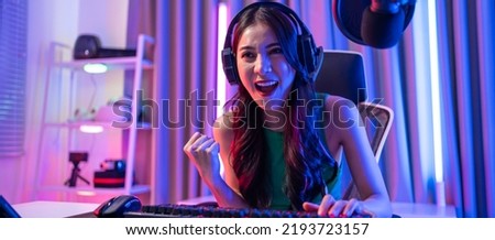 Asian beautiful Esport woman gamer play online video game on computer. Attractive young girl gaming player feel happy and enjoy technology broadcast live streaming while plays cyber tournament at home