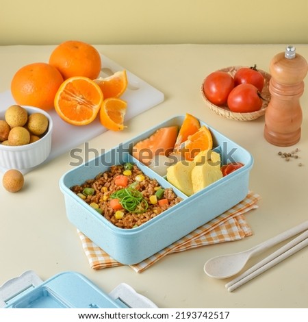Prepare Children's School Supplies in the lunch box, with ingredients vegetables fried rice, tamagoyaki or omelet, orange, melon, and longan.  Royalty-Free Stock Photo #2193742517