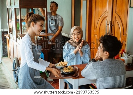 female waitress serving chicken noodles and fried noodles on a tray to customers Royalty-Free Stock Photo #2193753595