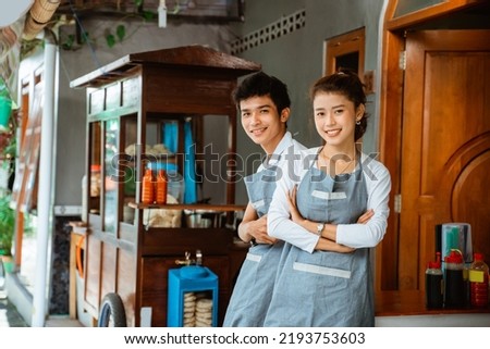 female and male traders smiling with arms crossed at a chicken noodle cart stall Royalty-Free Stock Photo #2193753603