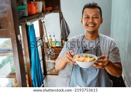 man seller smiling while bringing a bowl of chicken noodles for customers in a stall cart Royalty-Free Stock Photo #2193753615