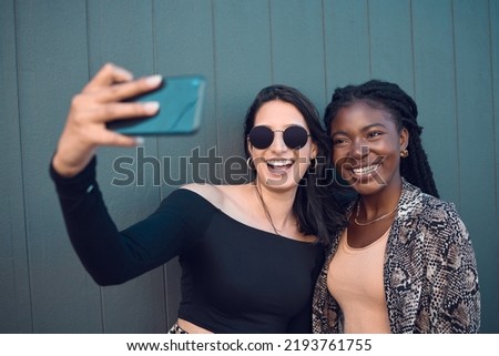 Happy girl friends taking a selfie on phone while traveling around the city on summer vacation. Diversity, love and smiling women taking picture on smartphone to post on social media and the
