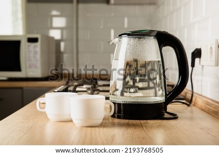 Modern electric transparent kettle on a wooden table in the kitchen.Kettle for boiling water and making tea.Home appliances for making hot drinks.Space for copy.Place for text. Royalty-Free Stock Photo #2193768505