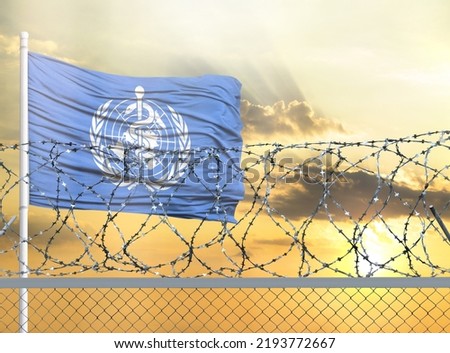 Flagpole with the flag of WHO against the sky and behind a fence with barbed wire. The concept of protecting the borders of territories.
