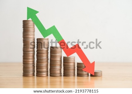Stack coins and arrow red green graph chart volatility up and down on wooden table background. Business, financial and investment concept. Risk, fluctuation in stock market and cryptocurrency.