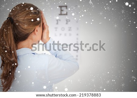 Composite image of brunette woman making an eye test against snow