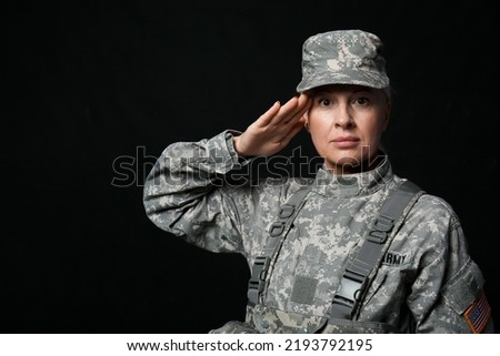 Mature female soldier saluting on black background