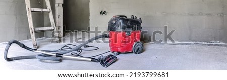 Red industrial vacuum cleaner at new house construction site, wide banner photo, space for text right side