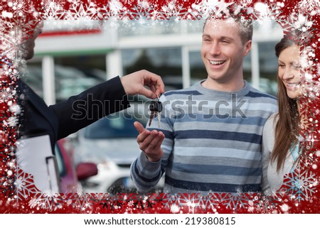 Composite image of couple receiving car keys by a dealer against snow