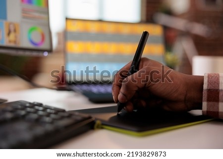 Male photographer using graphic tablet and stylus to retouch image, working on creative media production with editing software and multimedia interface. Retouching photos with app. Close up.