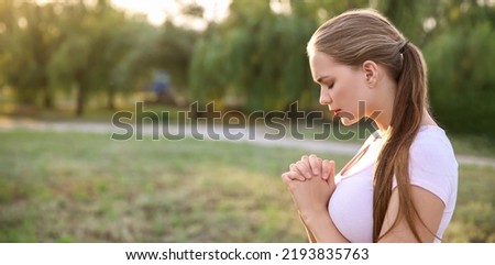 Young woman praying to God outdoors
