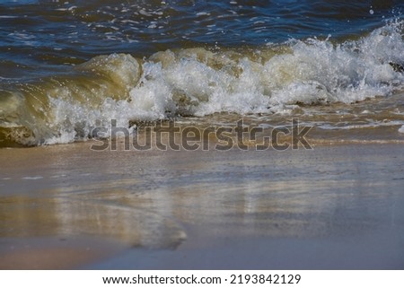 Breaking waves at a sandy beach on a sunny day