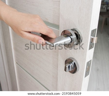A man's hand opens an interior door with a broken doorknob. Poor quality door hardware, breakage, damage. Close-up Royalty-Free Stock Photo #2193845059
