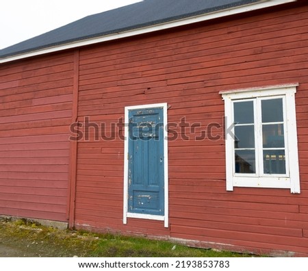 Red wooden house with window and door. Old facade architecture in vintage style. Close up and background. The northernmost civilian settlement in the world.
Seen in Ny Alesund, Svalbard, Norway.
