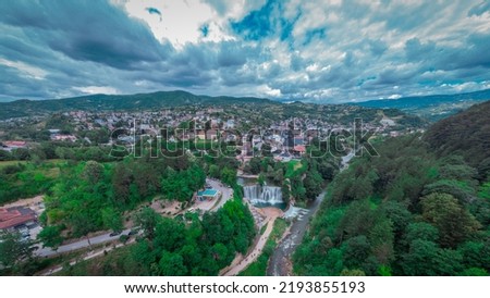 Pliva river waterfall and panorama of Jajce city in western Bosnia. Drone perspective or aerial photo of Jajce in a cloudy day.