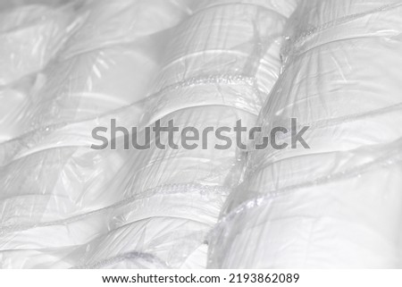 Many new rolls of toilet paper and paper towels sealed in stock. Light industry. Production of essential goods. Light background.