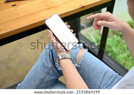 A female in the coffee shop using her smartphone to chat with her friends, phone white screen mockup. close-up image