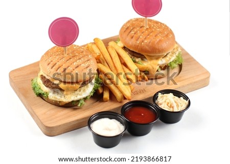 Two delicious homemade burger with beef, tomatoes, cheese, arugula and chard on a wooden cutting board.  fast food. white background.