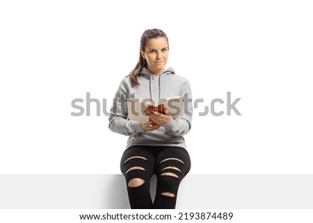 Girl sitting on a panel and holding a book isolated on white background