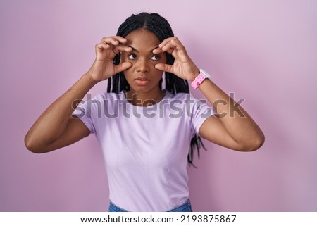African american woman with braids standing over pink background trying to open eyes with fingers, sleepy and tired for morning fatigue 