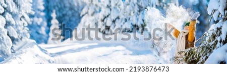 Happy little girl playing with snow throwing up snowflakes. Love winter concept. Heart from scattered snowflakes.