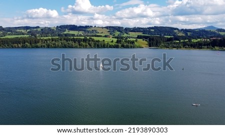 Aerial drone shot of lake with sailboats and stand up paddler
