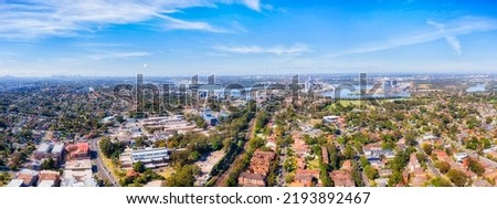Cityscape of Sydney city skyline over Western Sydney city of Ryde suburbs on shores of Parramatta river - aerial landscape.