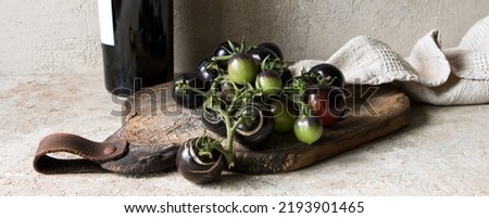 a bottle of wine and black tomatoes on a wooden board