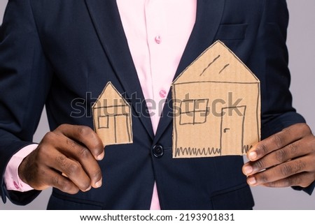 a black man holding two cardboard house