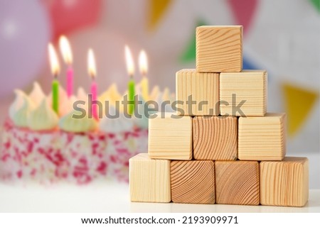 The pyramidal shape is built from a wooden cube on the background of a cake with lit candles. Banner mockup for display or design montage, business growth concept to success.