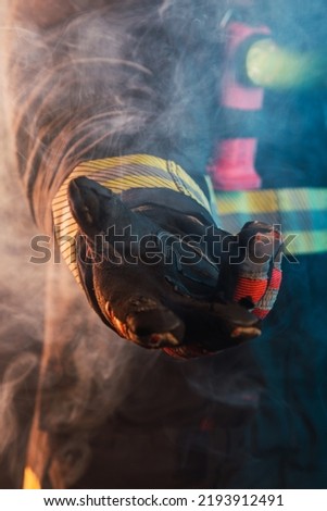 Fireman's hand giving help at fire with smoke.  Night image with flashlight on.