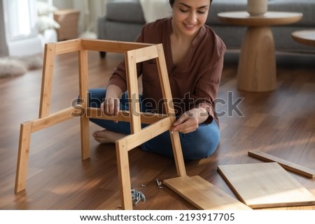 Decorating flat. Cropped shot of busy young female engaged in easy construction of modern wooden shelf. Focused millennial woman use simple tools to furnish room by self assembly furniture Royalty-Free Stock Photo #2193917705