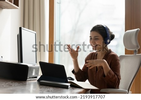 Social distance in office work. Young Indian female team leader in earphones meet staff online provide virtual training speak using touchpad webcam. Business lady talk on internet briefing