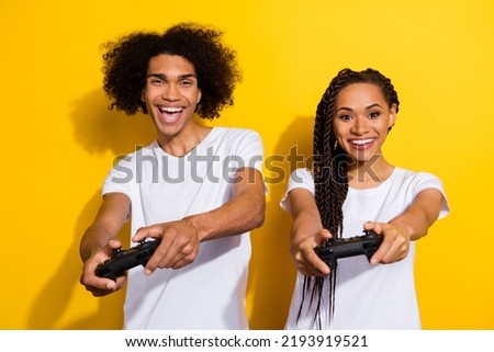 Photo of two excited crazy people hands hold controllers play games isolated on yellow color background