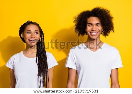 Photo of two cheerful positive people look interested each other toothy smile isolated on yellow color background