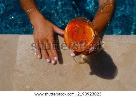 Woman holding aperol spritz cocktail on summer party by the pool. Event celebration concept. Royalty-Free Stock Photo #2193923023