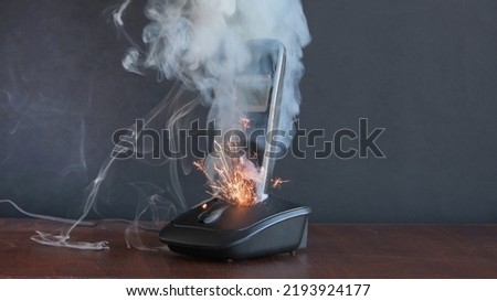 the radiotelephone smokes and burns, sparks fly, a short circuit in household electrical appliances and household appliances. Concept: house fire and electrical wiring fires. Royalty-Free Stock Photo #2193924177