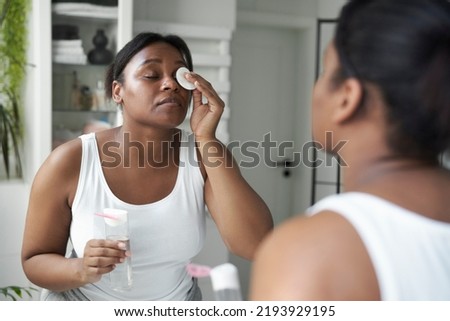 African-American woman removing make up in the bathroom Royalty-Free Stock Photo #2193929195