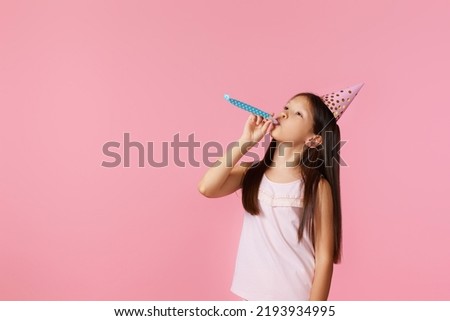 happy little birthday girl with party cone hat and whistle