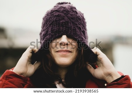 pull head wool cap autumn winter casual woman wearing wool hat outdoors hiding her eyes under fashion knitted cap. Winter wool hat for the cold outside. Crochet wool winter hat Royalty-Free Stock Photo #2193938565