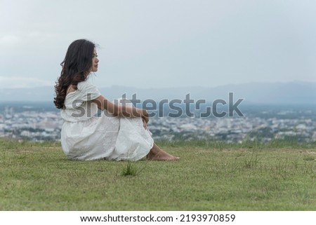woman sit facing side on grass at top mountian look at sky  nature view. feel relax. Royalty-Free Stock Photo #2193970859